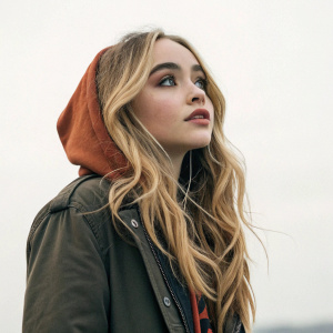 Sabrina Carpenter standing alone, no background visible, focused on camera. Mention of her role in 'Because I Liked a Boy' music video.