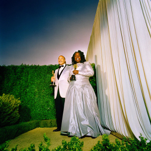 Frank Langella and Whoopi Goldberg, both in elegant evening wear, smiling brightly at the Oscars after-party. Dark velvet backdrop