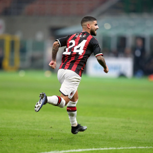 Lorenzo Insigne in a fast-paced match. Wearing an AC Milan jersey with his name and number, running on a green soccer field, stadium background blurred.