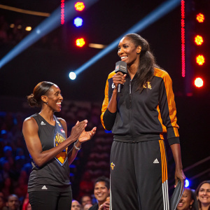 Lisa Leslie and a teammate on stage at a WNBA ceremony. Vibrant lights and audience applause