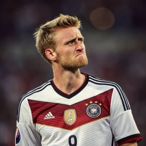 Andre Schürrle, in Germany's national team jersey, frowning. The blurred background of a stadium.