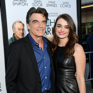 Peter Gallagher and Kathryn Gallagher at the 'Thanks for Sharing' film premiere. Peter, a white male with a bald spot and a welcoming grin, in a dark blazer and blue shirt. Kathryn, a white female with a warm smile, in a black leather dress. The backdrop features a movie poster with other actors and text.
