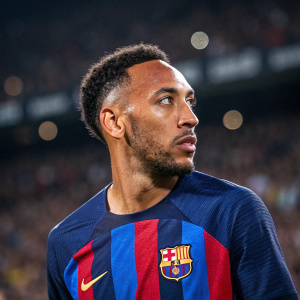 Close-up of Pierre-Emerick Aubameyang at FC Barcelona stadium. Player wears blue and red jersey with FC Barcelona crest and Spotify logo. Intense gaze.