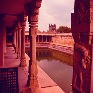 Aerial view of Airavatesvara Temple in Darasuram, Tamil Nadu, India. Stone pillars and intricate carvings of elephants and horses. Set beside a serene water body, showcasing earthy tones.