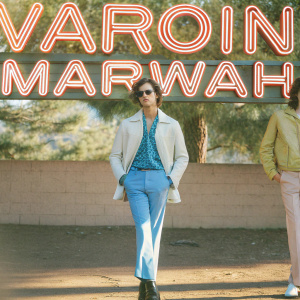 Model showcasing Varoin Marwah Menswear collection. Neon 'VAROIN MARWAH' text dominating the background.