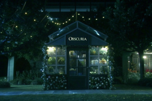 Create a Flower shop named "Obscuria" that specializes on selling
exotic and magical flowers and plants.
The flower shop is small and cozy, looks
fantastical and is covered in floral elements. The shop is located among
modern day buildings and industrial houses.