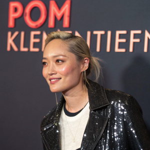 Pom Klementieff, Asian actress, in a candid photo. She is wearing a casual, stylish outfit with a black sequined jacket. Smiling subtly. Dark background with bright, bold text.