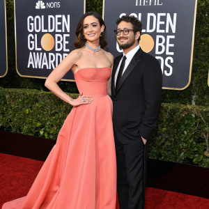 At the annual Golden Globe Awards, Emmy Rossum in a striking pink off-the-shoulder gown. Sam Esmail, wearing a classic black suit and glasses, joins her on the vibrant red carpet.