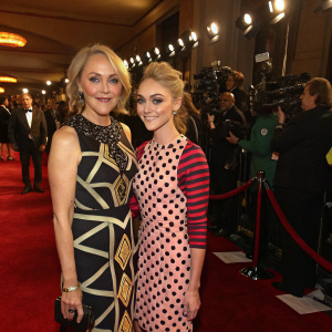 Janet Robb and Annasophia Robb attend the annual film gala. Janet dons a chic, geometrically patterned dress, while Annasophia opts for a vibrant polka-dotted ensemble. Crowded venue with red carpet and flashing cameras.