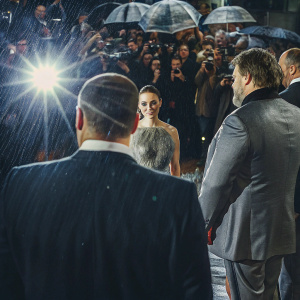 At the premiere of 'Noah', Russell Crowe, Jennifer Connelly, and Darren Aronofsky. Crowded event, flashing lights. Crowe in black tux, Connelly in elegant gown, Aronofsky in tailored suit.
