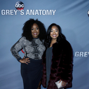 Shonda Rhimes and Harper Rhimes at the celebratory event for the 300th episode of Grey's Anatomy. Shonda wears a striking black and white top, standing elegantly beside Harper, dressed in a dark burgundy, fur-textured dress. The backdrop features bold ABC and Grey's Anatomy logos.