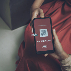Smartphone display featuring Paytm app with promo for cashback offer. Includes special promo code and QR code