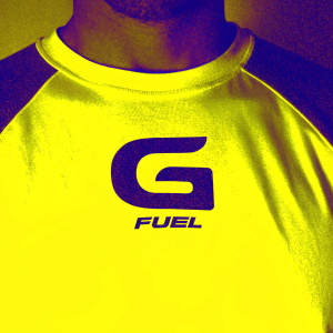 Close-up of a white t-shirt with bold G FUEL logo in dark green. Simple studio setup, plain white background.