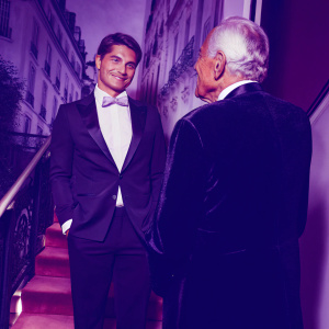 Josh Hartnett and Giorgio Armani at the Met Gala. Hartnett in a dark suit, Armani in dark velvet tuxedo and white shirt. Backdrop of ornate buildings.