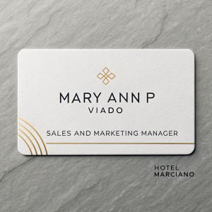 Professional business card for Mary Ann P Viado, Sales and Marketing Manager at Hotel Marciano. Sleek design with clear, readable text and icons. White background, minimalist logo on right.