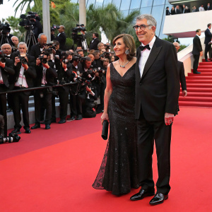 Elliott Gould and Jennifer Bogart at the Cannes Film Festival. Red carpet event with flashing cameras and paparazzi.