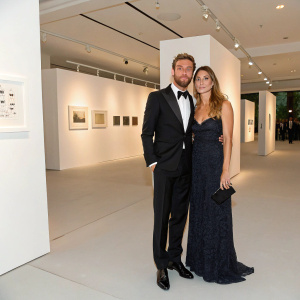 Claudio Marchisio and Roberta Sinopoli at a glamorous gala. The venue is a modern art gallery with stark white walls and minimalist decor.