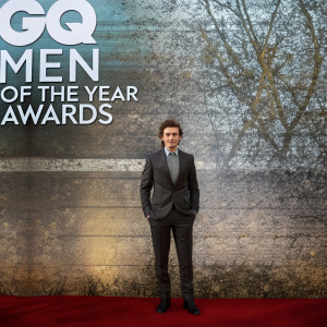 Callan McAuliffe, young actor, at GQ Men of the Year Awards. Turquoise backdrop, bold white text