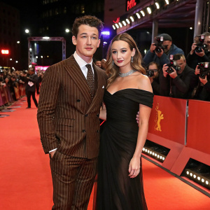 Miles Teller and Keleigh Sperry at a glamorous movie premiere. Miles in a sharp brown pinstripe suit, Keleigh in an elegant black off-the-shoulder gown. Red carpet bustling with paparazzi.