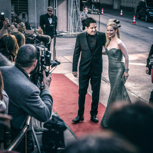 Kathryn Newton and David Dastmalchian attend the Ant-Man and The Wasp premiere party. Kathryn in a sparkling green gown, David in a black tuxedo. Red carpet and flashing cameras