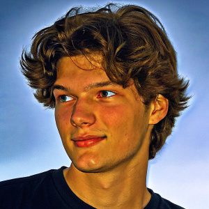 Digital portrait of Bryan Dechart, a young Caucasian male with wavy brown hair and medium build. He wears a black t-shirt. The illustration focuses on his face with realistic lighting and shading, set against a plain white background. His youthful and engaging expression is highlighted.