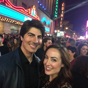 Brandon Routh and Courtney Ford, smiling broadly. Crowded scene from the MTV Movie Awards. Neon lights and bustling crowd in the background.