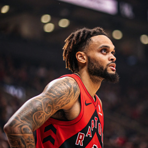 Gary Trent Jr., basketball player for Toronto Raptors, red jersey, posing with tattoos visible. Sporty pose, indoor arena backdrop