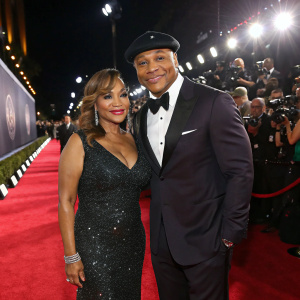 Simone Smith and LL Cool J on a glamorous red carpet. Bright lights and photographers in the background.