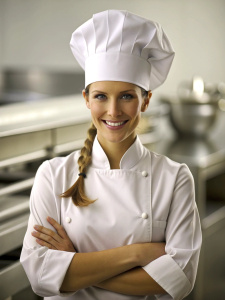 Caucasian young women chef in a chef's hat with arms crossed wears apron standing in restaurant kitchen and smiling