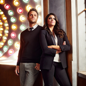 Mike O'Brien and Cecily Strong attending the Adweek Hot List Gala. Both are dressed formally. Mike in a dark sweater with tie. Cecily in a black blazer. They stand confidently against a vibrant, neon-lit backdrop.