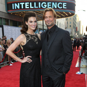 Meghan Ory and Josh Holloway, dressed in evening wear, attending the premiere of 'INTELLIGENCE'. Red carpet scene with flashing cameras.
