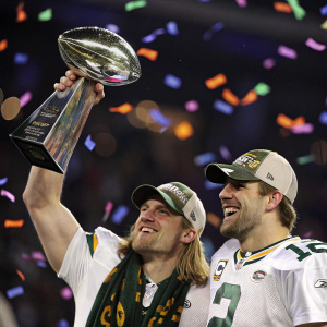 Aaron Rodgers and Clay Matthews celebrating the Super Bowl victory with the Lombardi Trophy. Cheerful expressions, surrounded by confetti.