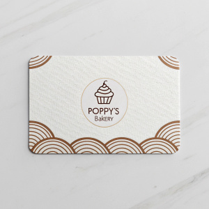 Business card for Poppy's Bakery. Sleek and modern design. White background with subtle brown accents. Large logo. Minimalistic layout.