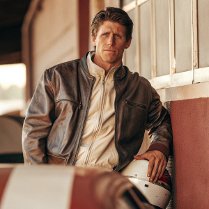 Carl Edwards, racing driver, posing for a formal photo shoot. Black leather jacket, dark background.