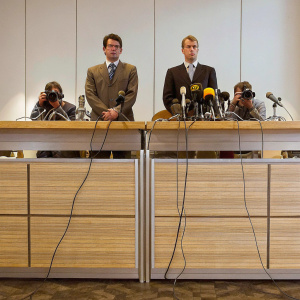 Fabio Capello and Stuart Pearce during a press conference. Both are dressed in suits, serious expressions.