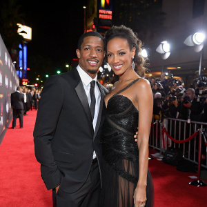 Nick Cannon and Selita Ebanks on the red carpet. Posing for photographers. Bright lights and crowd visible in the background.