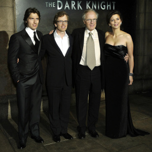 Christian Bale, Gary Oldman, Michael Caine, and Maggie Gyllenhaal at The Dark Knight movie premiere. They wear formal attire and stand together. Dark colored backdrop with movie name and logo