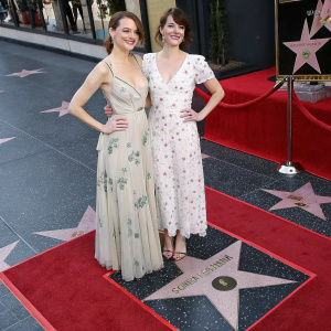 Emma Stone and Martha Macisaac on Hollywood's Walk of Fame. Wearing elegant gowns, posing with confidence.