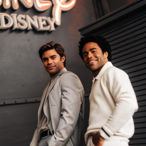 Zac Efron and Corbin Bleu posing for a promotional shot for High School Musical. Vibrant Disney logo backdrop.