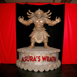 High-definition render of a golden Asura's Wrath statue. Mythical, muscular beast with multiple arms in an aggressive stance. Ornate, golden base with 'Asura's Wrath' text in flowing script. Dark backdrop