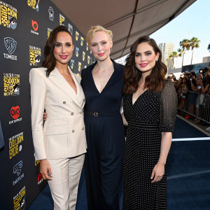 Gal Gadot, Gwendoline Christie, and Hayley Atwell at San Diego Comic-Con. Wearing formal outfits. Dark blue carpet with logos