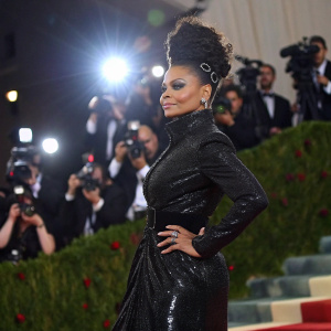 Janet Jackson, in a black sequined dress, at the Met Gala. Flashing lights from photographers in the background.