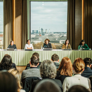 Press conference for 'Elisa y Marcela' at Berlin Film Festival. Grand Hyatt Hotel. Panelists: Greta Fernandez, Isabel Coixet, Natalia de Molina, Anatol Weber. Backdrop: Cityscape. Audience: Diverse. Atmosphere: Formal, focused.
