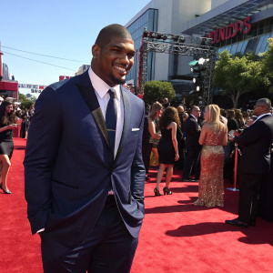 Michael Sam, wearing a navy suit, at the ESPY Awards ceremony. A crowd of celebrities in the background