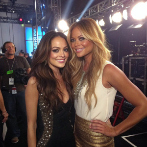 Lindsay Lohan and Vanessa Minnillo backstage at a music awards show. Candid, informal pose. Bright lights and crew visible