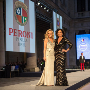 Landi Swanepoel and Nancy Dell'Olio at the annual Peroni Italia gala. Wearing designer outfits, standing on a stage with large Peroni Italia banners in the background.