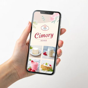 A mockup showcasing Cimory Indonesia's homepage. The layout is minimalist, with soft pastel colors. Features include the brand logo, high-quality product illustrations, and concise product descriptions.