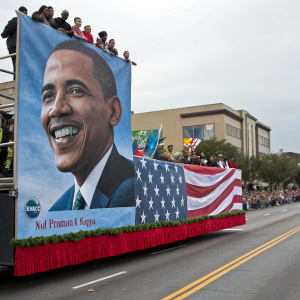 Barack Obama's face on a giant banner, Martin Luther King Jr. silhouette. Parade float in USA celebrating diversity, filled with enthusiastic people