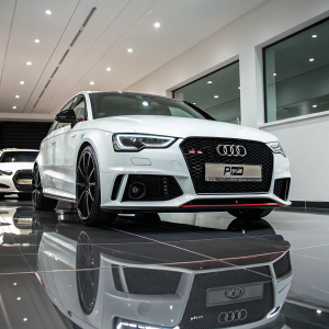 White Audi RS3 Sportback on display in RS Performance Cars showroom. Polished floor reflects the car's sleek design. Bright lighting highlights the prominent front grille and RS Performance Cars label.