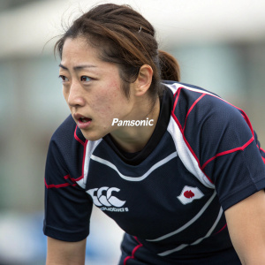Close-up of Japanese athlete Eriko Hirose. She wears a dark jersey with white and red accents and a Panasonic logo. The background is blurred, emphasizing her expression.
